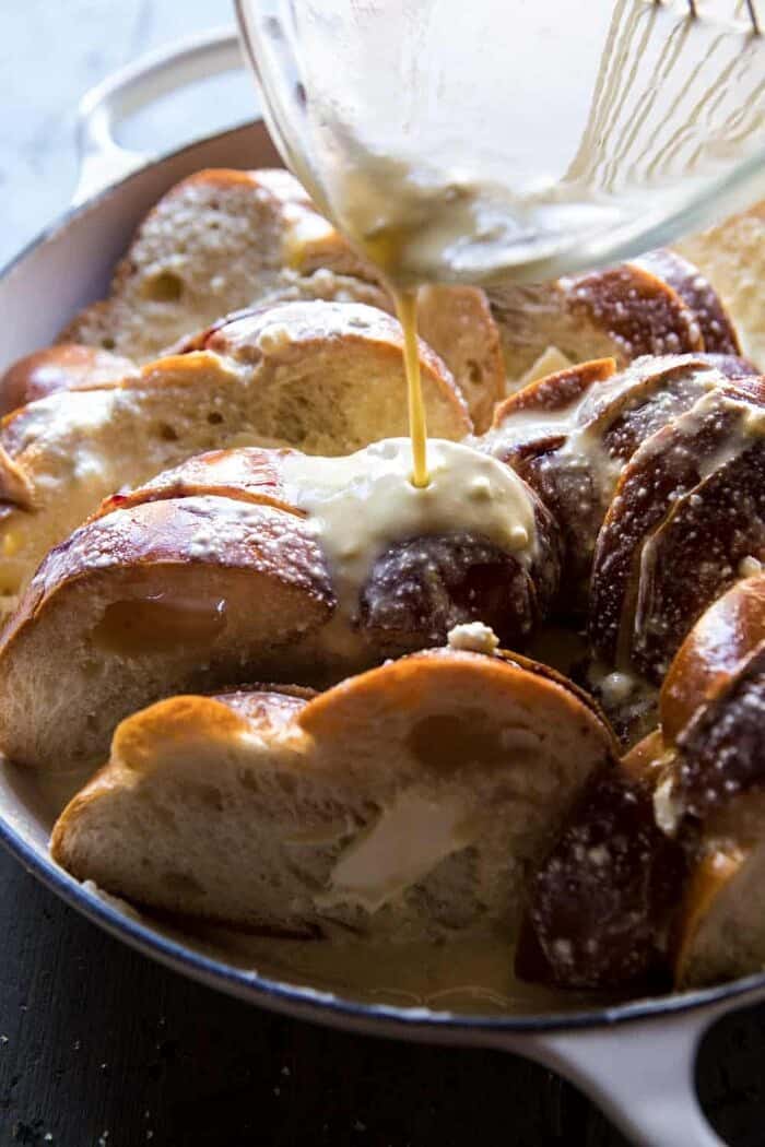 Baked Blackberry Ricotta French Toast | halfbakedharvest.com #breakfast #brunch #easy #recipes action shot of pouring egg batter over Baked Blackberry Ricotta French Toast