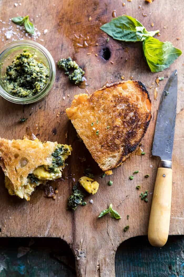 Breakfast Grilled Cheese with Soft Scrambled Eggs and Pesto | halfbakedharvest.com #breakfast #brunch #grilledcheese over photo of half eaten Breakfast Grilled Cheese with Soft Scrambled Eggs and Pesto