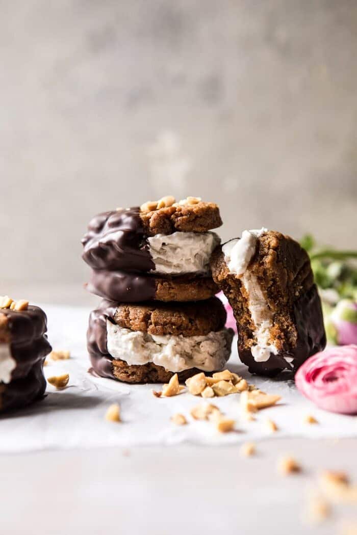 Chocolate Dipped Peanut Cookie Ice Cream Sandwiches | halfbakedharvest.com #icecream #chocolate #peanutbutter #summer stacked, front on photo of Chocolate Dipped Peanut Cookie Ice Cream Sandwiches with bite out of one sandwich