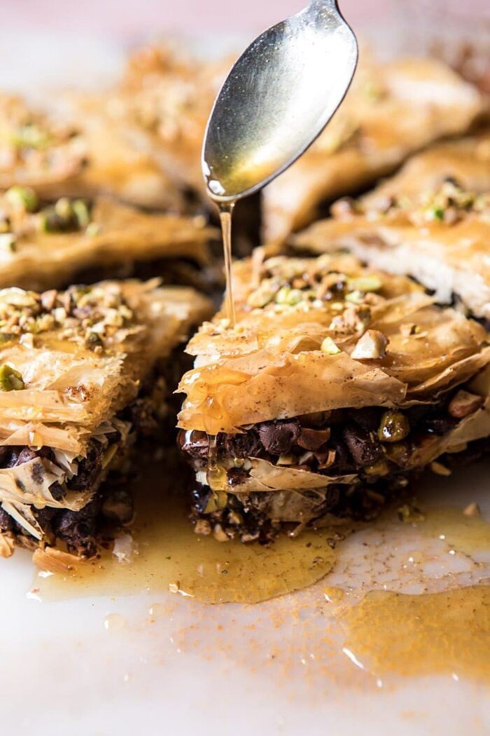 Easy Pistachio Chocolate Baklava | halfbakedharvest.com #greek #easydessert #chocolate drizzling honey over Easy Pistachio Chocolate Baklava, close up photo