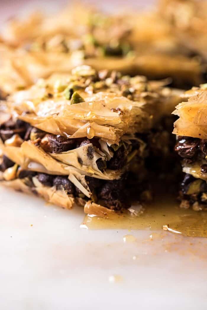 Easy Pistachio Chocolate Baklava | halfbakedharvest.com #greek #easydessert #chocolate side angle photo of Easy Pistachio Chocolate Baklava with honey dripping down
