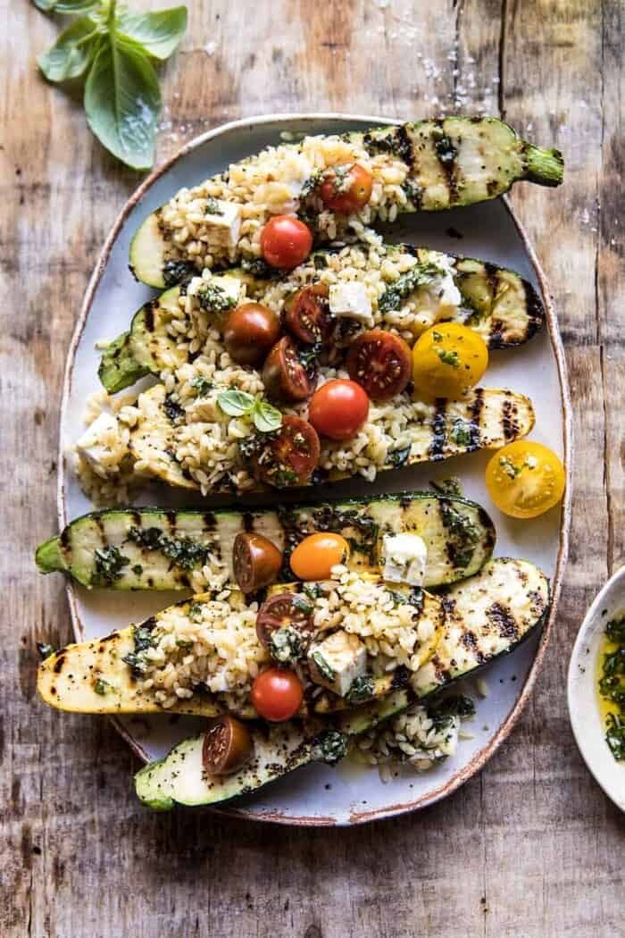 Grilled Pesto Zucchini Stuffed with Tomatoes and Orzo | halfbakedharvest.com #grilling #summer #easyrecipes overhead photo of Grilled Pesto Zucchini Stuffed with Tomatoes and Orzo