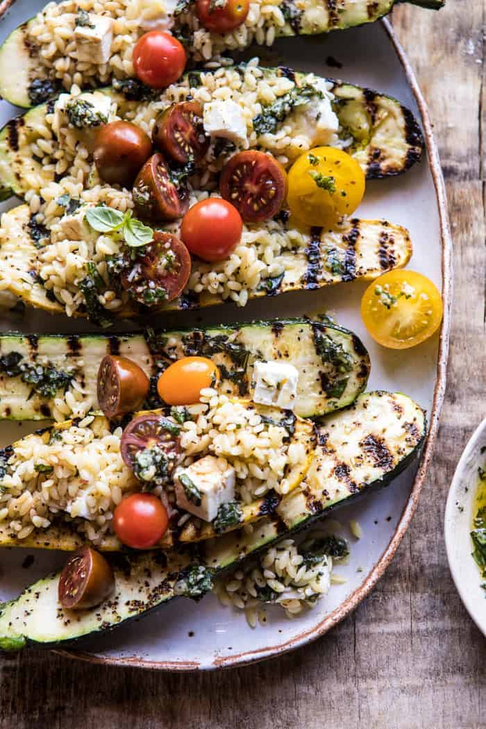 Grilled Pesto Zucchini Stuffed with Tomatoes and Orzo | halfbakedharvest.com #grilling #summer #easyrecipes close up photo of side angled Grilled Pesto Zucchini Stuffed with Tomatoes and Orzo