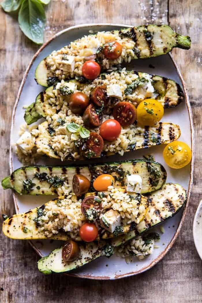 Grilled Pesto Zucchini Stuffed with Tomatoes and Orzo | halfbakedharvest.com #grilling #summer #easyrecipes close up overhead photo of Grilled Pesto Zucchini Stuffed with Tomatoes and Orzo
