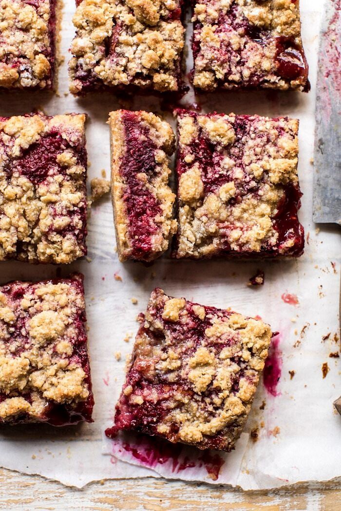 Buttery Raspberry Crumble Bars | halfbakedharvest.com #raspberry #dessert #summer #backtoschool #easyrecipes overhead photo of Buttery Raspberry Crumble Bar with one bar cut in half to show the filling