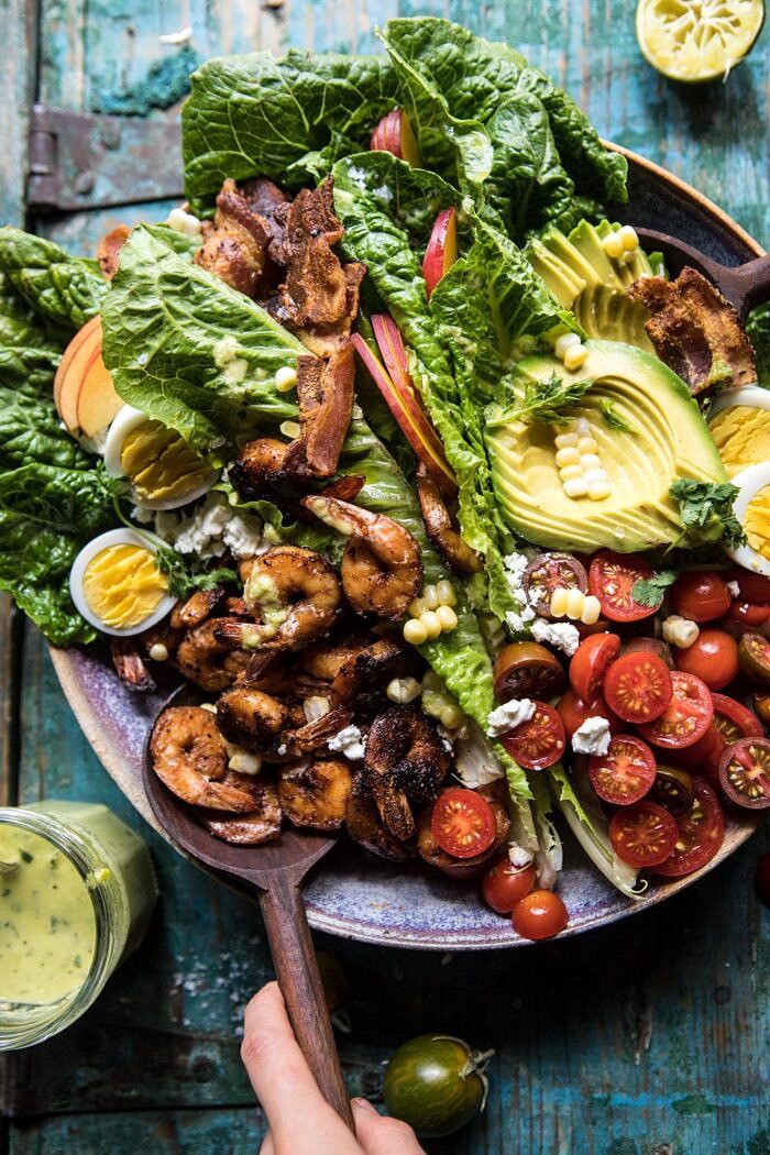 overhead photo of Chipotle Shrimp Cobb Salad with Jalapeno Corn Vinaigrette with salad tongs