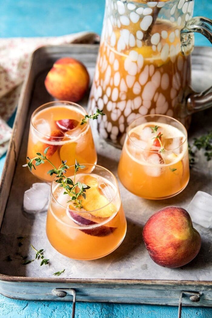 Sweet Bourbon Peach Lemonade | halfbakedharvest.com #peaches #bourbon #lemonade far out photo of Sweet Bourbon Peach Lemonade with pitcher and peach in photo and on a tray