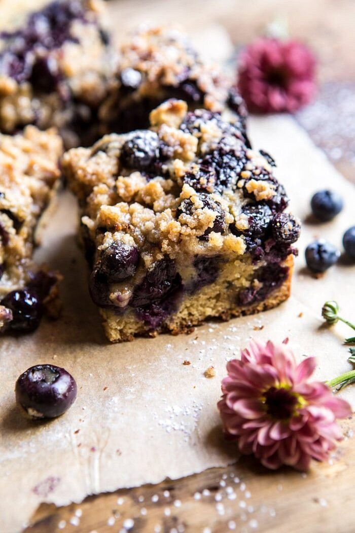 Bursting Blueberry Cardamom Buckle | halfbakedharvest.com #blueberry #cake #summerrecipes #easyrecipes #dessert side angle photo Bursting Blueberry Cardamom Buckle piece with flowers in photo