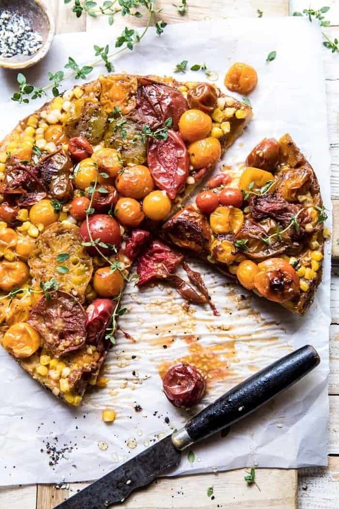 Caramelized Corn and Tomato Tarte Tatin | halfbakedharvest.com #simple #east #tomatoes #summer #tomatotart overhead photo of Caramelized Corn and Tomato Tarte Tatin with slices missing and knife in photo