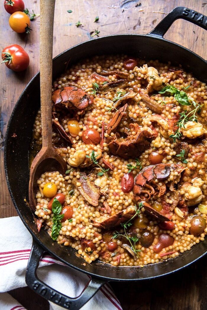 overhead photo of One Pot Tomato Basil Lobster and Herbed Pearl Couscous with wooden spoon in pot