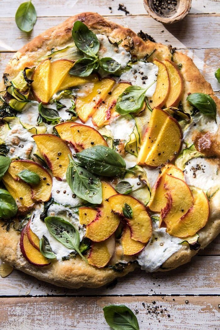 overhead photo of Pesto Zucchini and Peach Pizza with Burrata with sunlight on pizza