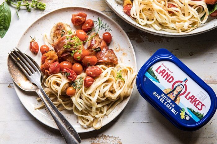 Prosciutto Chicken Parmesan with Garlic Butter Tomato Pasta | halfbakedharvest.com #pasta #easyrecipe #tomatoes #familyrecipes horizontal photo of Prosciutto Chicken Parmesan with Garlic Butter Tomato Pasta on plate with butter in photo