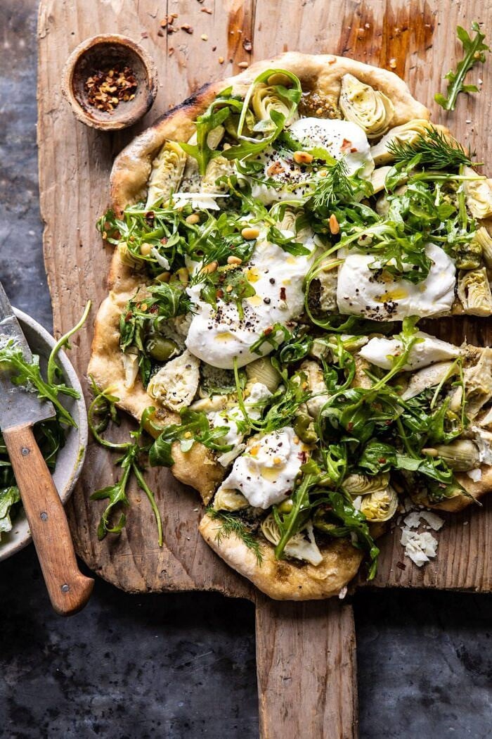overhead photo of Artichoke Pesto and Burrata Pizza with Lemony Arugula after being cut