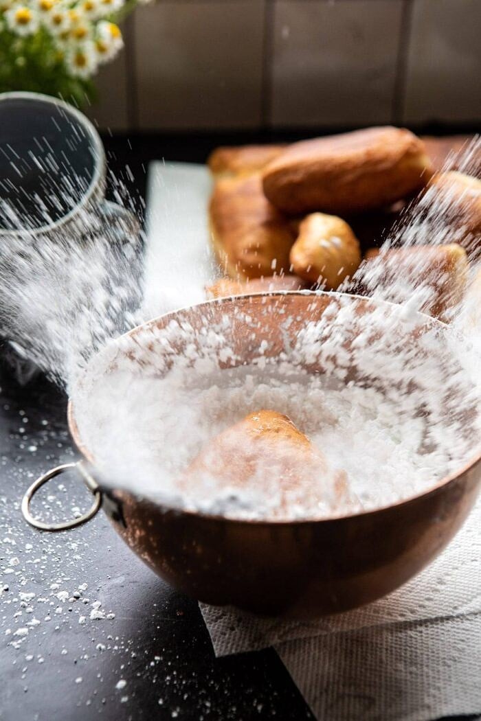 Beignets being coated in powdered sugar