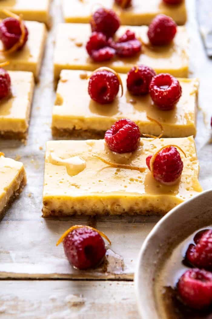 Creamy Lemon Bars with Browned Butter Raspberries | halfbakedharvest.com #lemon #brownbutter #spring #summer #easter #mothersday #brunch #dessert side angle photo of Creamy Lemon Bars with Browned Butter Raspberries