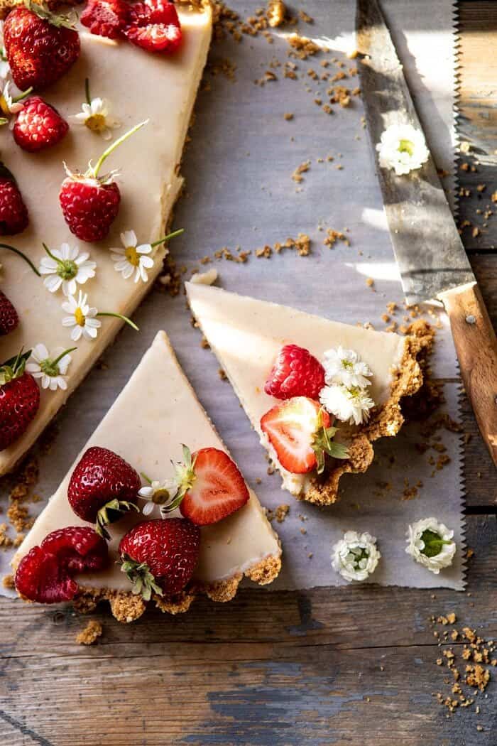 No Fuss Lemon Tart | halfbakedharvest.com #lemontart #dessert #summer #nobake #easyrecipes overhead close up photo of No Fuss Lemon Tart with 2 slices cut and 1 slice missing from tart