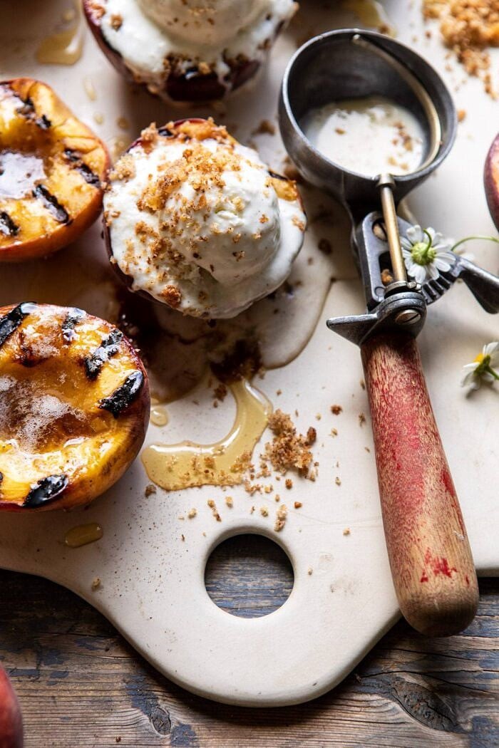 Browned Butter Grilled Peaches with Cinnamon Toast Brioche Crumbs | halfbakedharvest.com #summerrecipes #peaches #icecream #easyrecipes close up side angled photo of Browned Butter Grilled Peaches with Cinnamon Toast Brioche Crumbs on serving plate with ice cream scoop