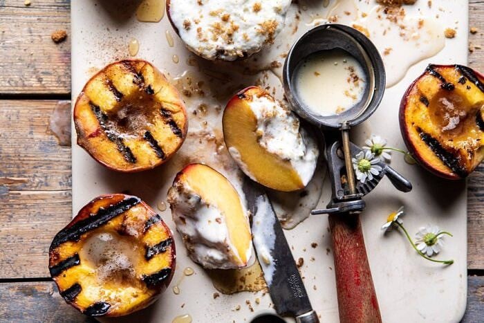 Browned Butter Grilled Peaches with Cinnamon Toast Brioche Crumbs | halfbakedharvest.com #summerrecipes #peaches #icecream #easyrecipes horizontal photo of Browned Butter Grilled Peach cut in half with Cinnamon Toast Brioche Crumbs