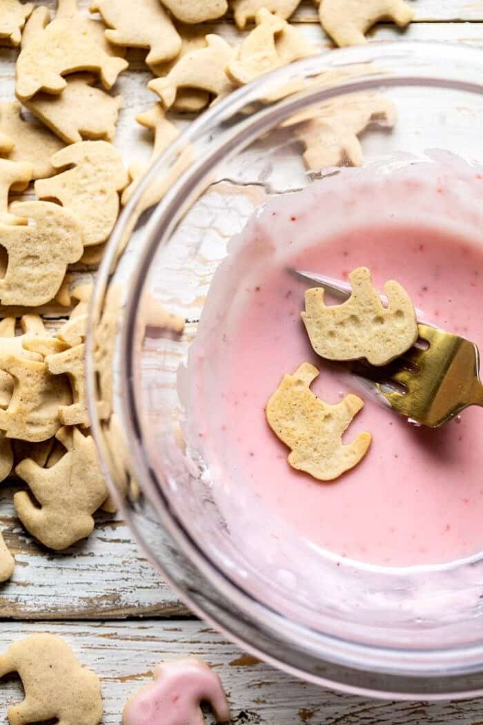 Homemade Animal Crackers | halfbakedharvest.com #crackers #homemaderecipes #cookies #snacks Homemade Animal Crackers being dipped in pink strawberry glaze