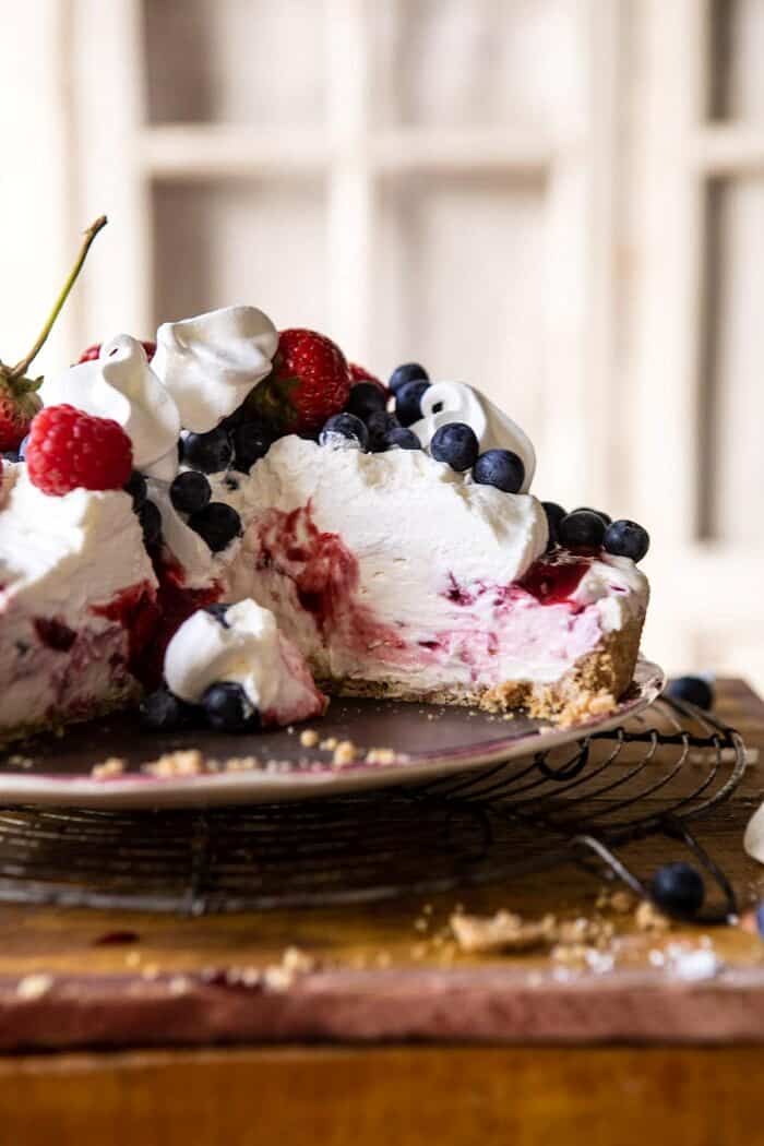 No-Bake Eton Mess Berry Cheesecake | halfbakedharvest.com #cheesecake #nonbake #easyrecipes #dessert #4thofjuly head on photo of No-Bake Eton Mess Berry Cheesecake with slice removed from cake