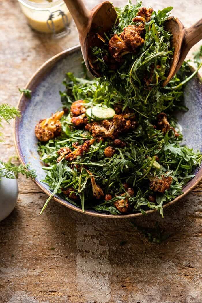 Roasted Cauliflower Salad with Creamy Honey Mustard Vinaigrette | halfbakedharvest.com #healthyrecipes #salad #cauliflower side angled photo of Roasted Cauliflower Salad with Creamy Honey Mustard Vinaigrette being tossed in salad bowl