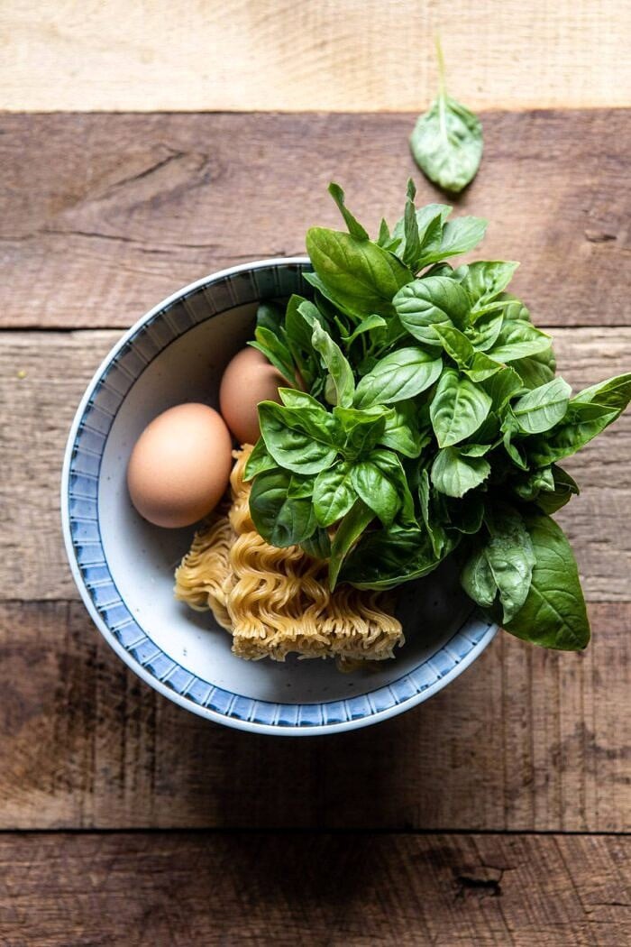 20 Minute Ramen Carbonara | #ramen #noodles #easyrecipes fresh basil, raw eggs, and uncooked ramen in a bowl before being prepared