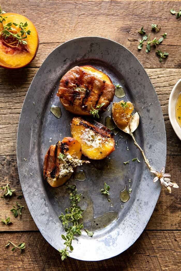 Prosciutto Goat Cheese Stuffed Peaches with Thyme Honey | halfbakedharvest.com #peaches #appetizer #goatcheese overhead photo of Prosciutto Goat Cheese Stuffed Peaches with Thyme Honey with peaches remove from platter and peach cut in half