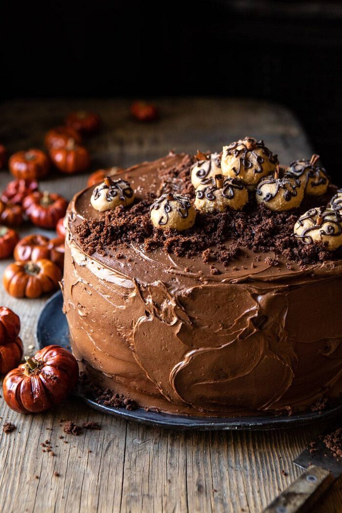 Pumpkin Patch Chocolate Peanut Butter Cake | halfbakedharvest.com #chocolatepeanutbutter #chocolatecake #peanutbutter #halloween close up slide angled photo of Pumpkin Patch Chocolate Peanut Butter Cake with mini pumpkins in the background