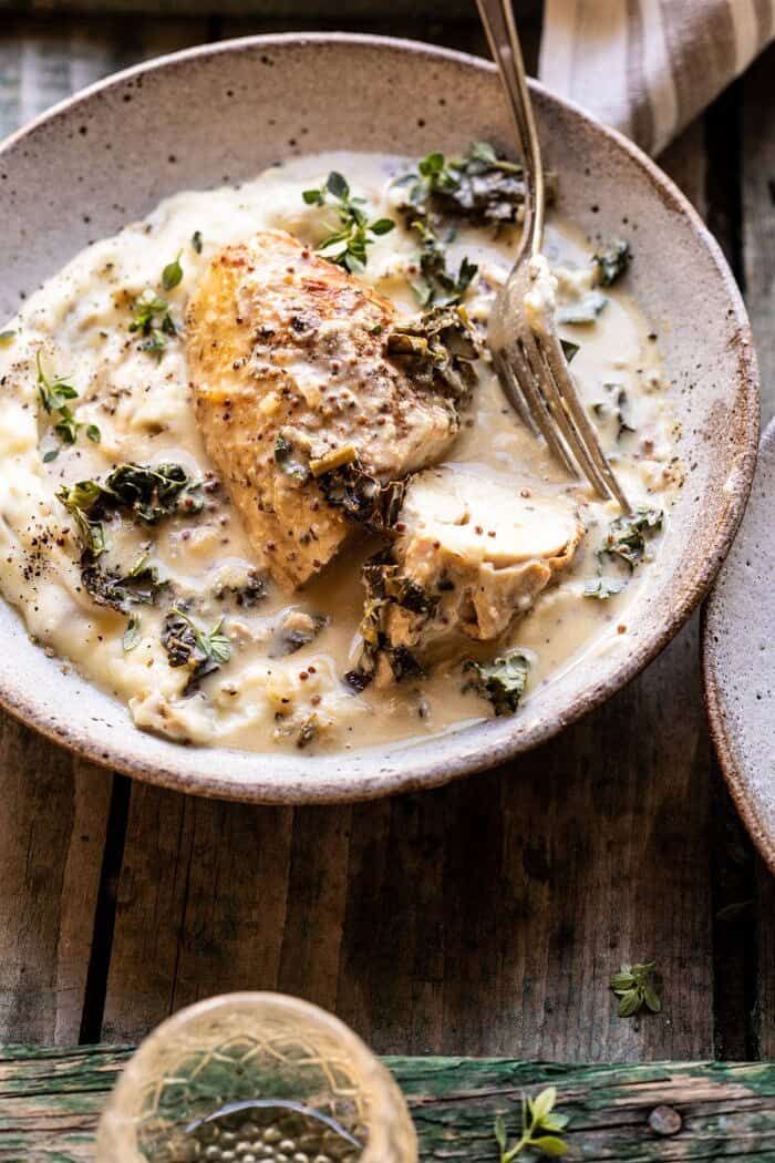 side angled photo of Slow Cooker French Wine and Mustard Chicken with chicken cut in half and sitting in mustard sauce