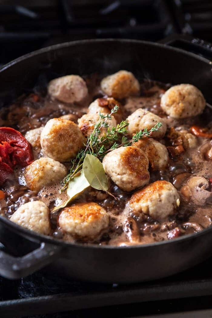 side angle photo of adding meatballs to skillet