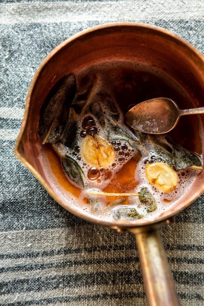Parmesan Popovers with Crispy Sage Garlic Butter | halfbakedharvest.com #popovers #bread #easyrecipes overhead photo of browned butter with sage and garlic in small saucepan