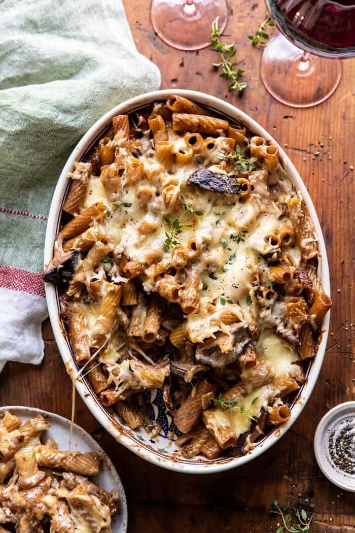 One Pot Creamy French Onion Pasta Bake | halfbakedharvest.com #pasta #frenchonion #easyrecipes overhead photo of One Pot Creamy French Onion Pasta Bake with serving of pasta removed and sitting on a plate next to dish
