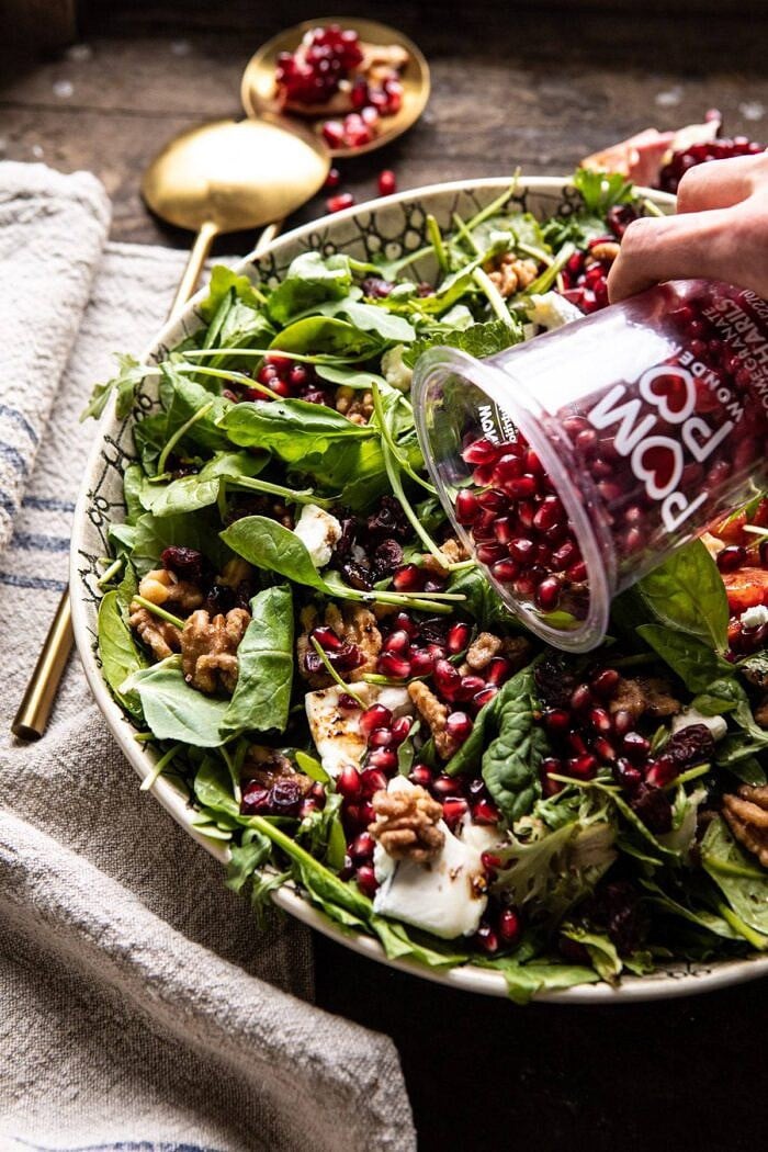Winter Pomegranate Salad with Maple Candied Walnuts | halfbakedharvest.com #wontersalad #healthy pomegranates being pour over Winter Pomegranate Salad with Maple Candied Walnuts