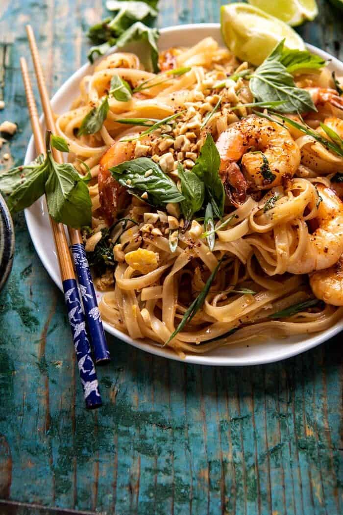 Better Than Takeout Garlic Butter Shrimp Pad Thai | halfbakedharvest.com #padthai #garlicbutter side angled photo of Better Than Takeout Garlic Butter Shrimp Pad Thai with chopsticks on the side of plate