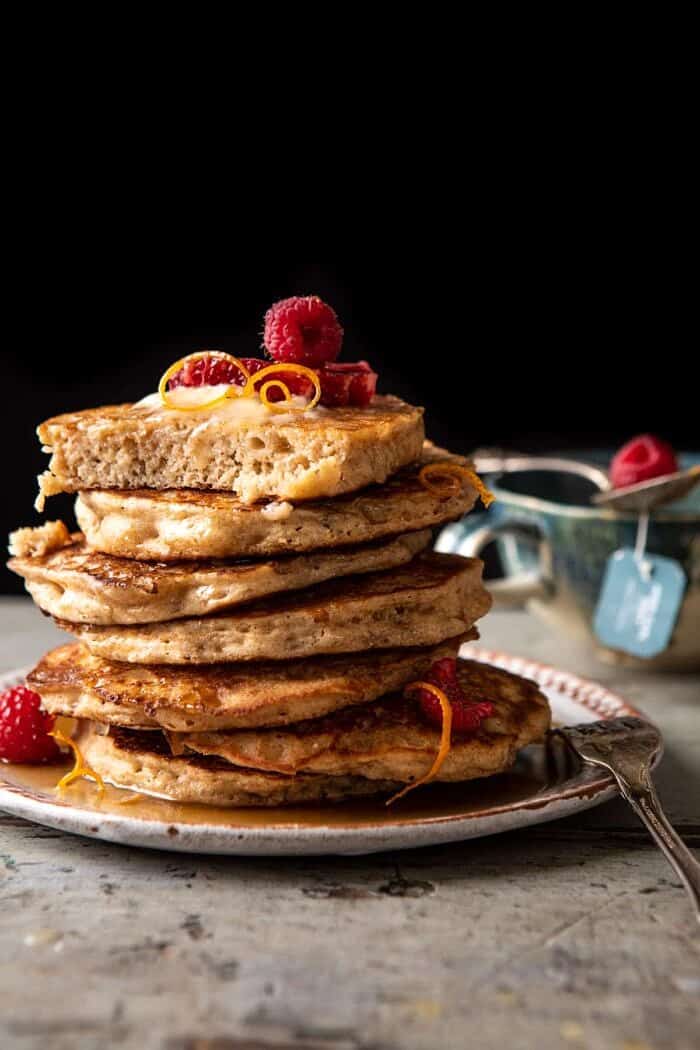 side angled photo of Earl Grey Lemon Ricotta Pancakes with Salted Maple Butter with a bite taken out of top pancake 