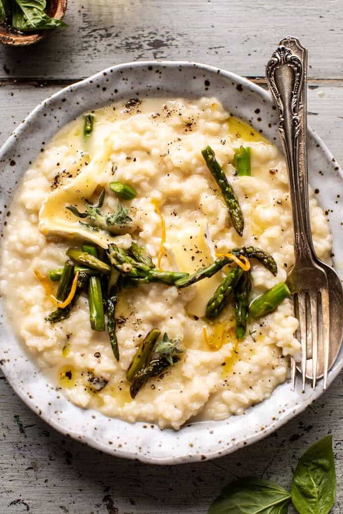 No Stir Brie Risotto with Lemon Butter Asparagus | halfbakedharvest.com overhead close up photo of No Stir Brie Risotto with Lemon Butter Asparagus and spoon in risotto bowl