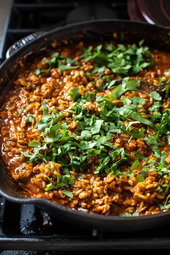 One Skillet Saucy Chicken Tortilla Enchilada Rice Bake | halfbakedharvest.com prep photo of skillet with meat and sauce before adding the chips