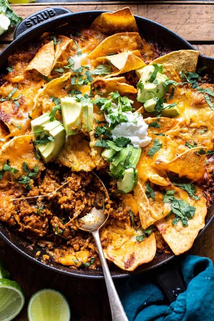 One Skillet Saucy Chicken Tortilla Enchilada Rice Bake | halfbakedharvest.com photo of One Skillet Saucy Chicken Tortilla Enchilada Rice Bake with spoon in skillet pulling up the rice to serve