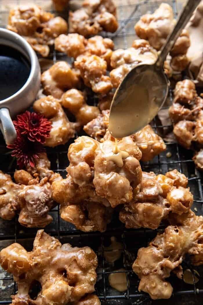 Cinnamon Spiced Apple Fritters with Vanilla Coffee Glaze | halfbakedharvest.com photo of Cinnamon Spiced Apple Fritters with Vanilla Coffee Glaze being drizzle over each fritter