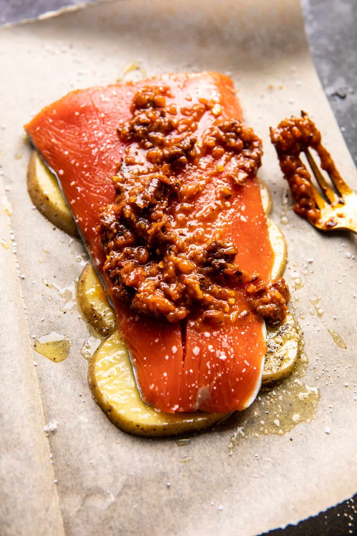 raw salmon on parchment with potatoes before baking 