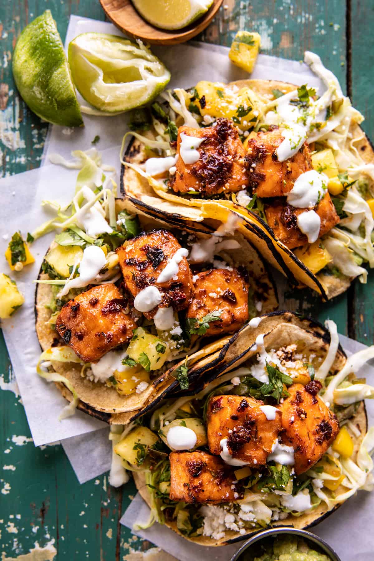 overhead photo of salmon tacos on serving board with toppings and limes 