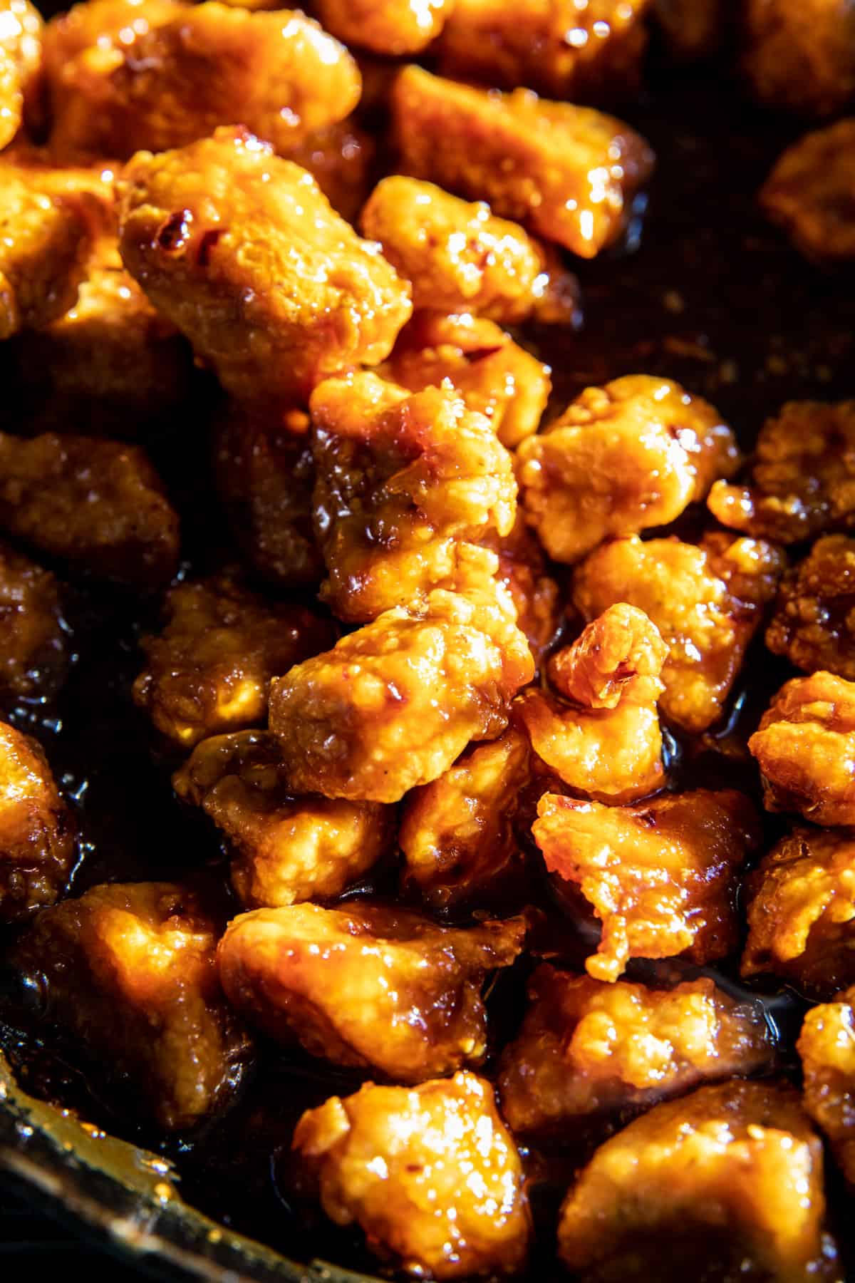 zoom in photo of orange chicken cooking in skillet