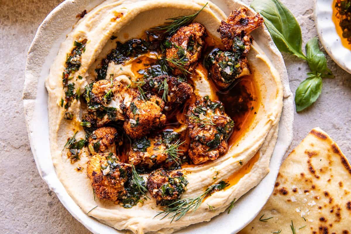 cauliflower in bowl with hummus and herb oil